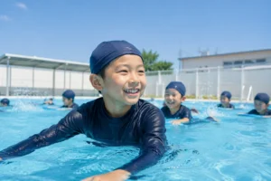 学校のプール授業でラッシュガードを着る小学生