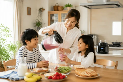 小学生ママが朝のキッチンで家族分のスムージーを作り、小学生の子ども2人へ注ぐ朝食風景