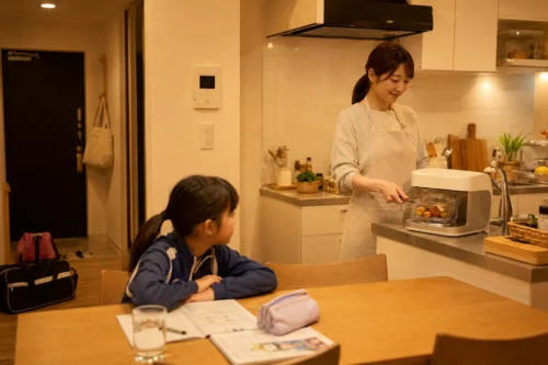習い事帰りの小学生の夕飯を小さな容器で温め直す様子